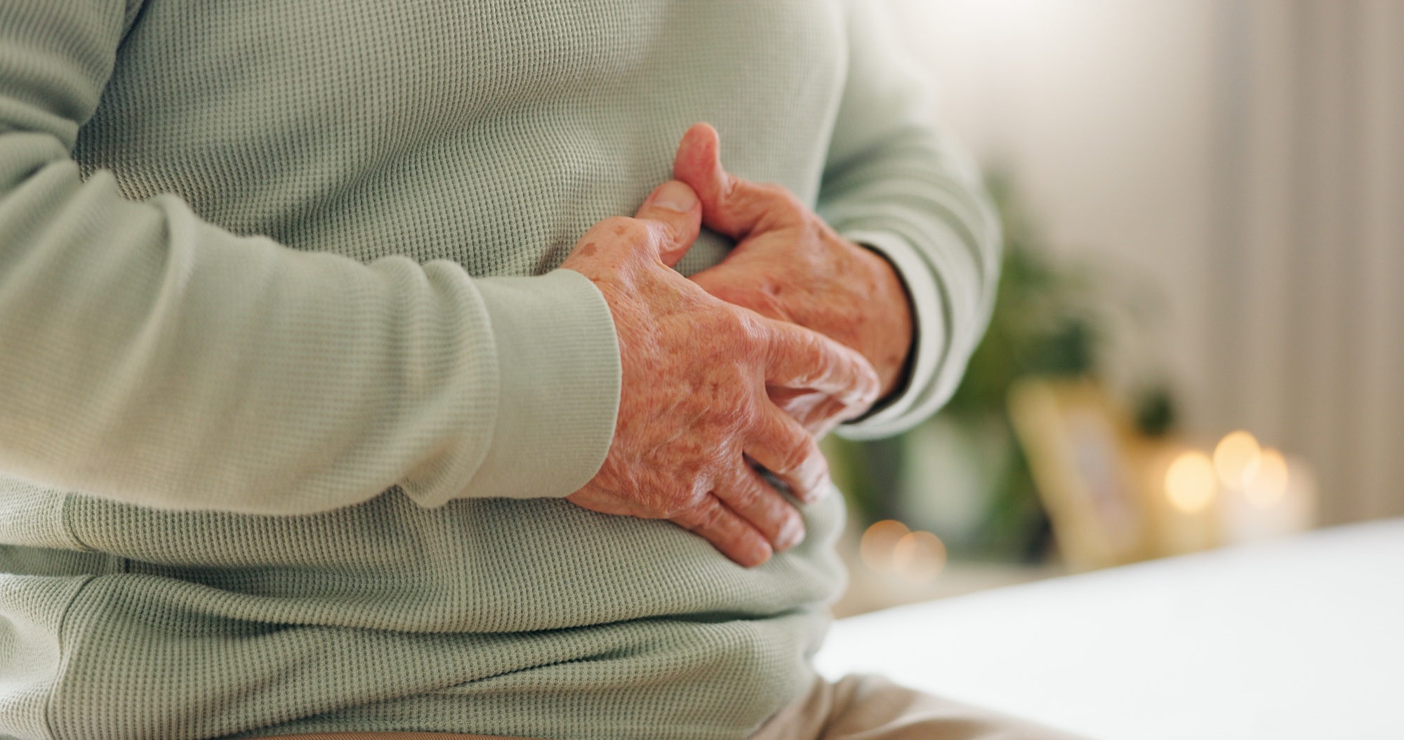 Hands, stomach pain with closeup and gut health, person has digestion issue and nutrition with elde